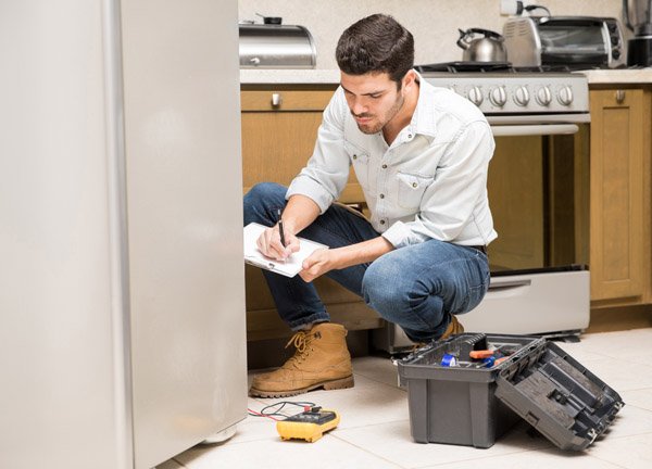 portrait handsome male technician doing work report broken fridge home kitchen (1)